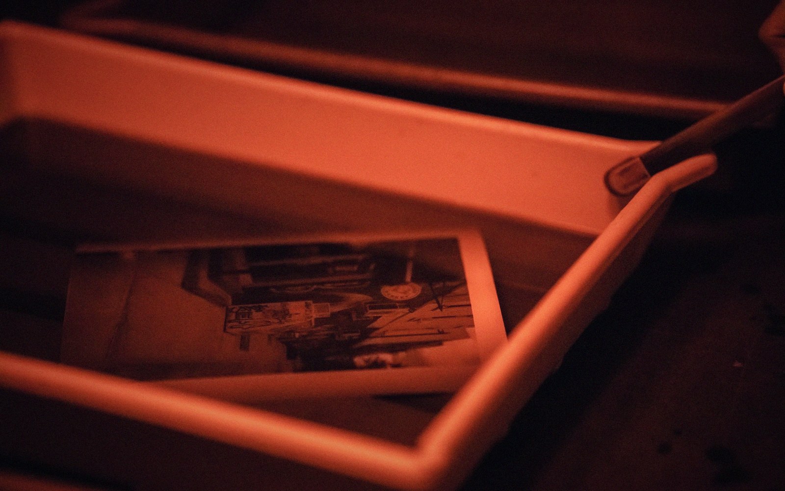 An old black-and-white photograph resting inside an open box, bathed in red light